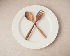 white plate with wooden spoon and fork crossed over each other in the center, forming an x