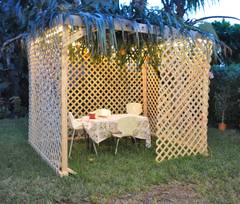homemade sukkah in the backyard with table and chairs set up inside.
