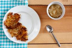 plate of golden brown latkes with a side of applesauce